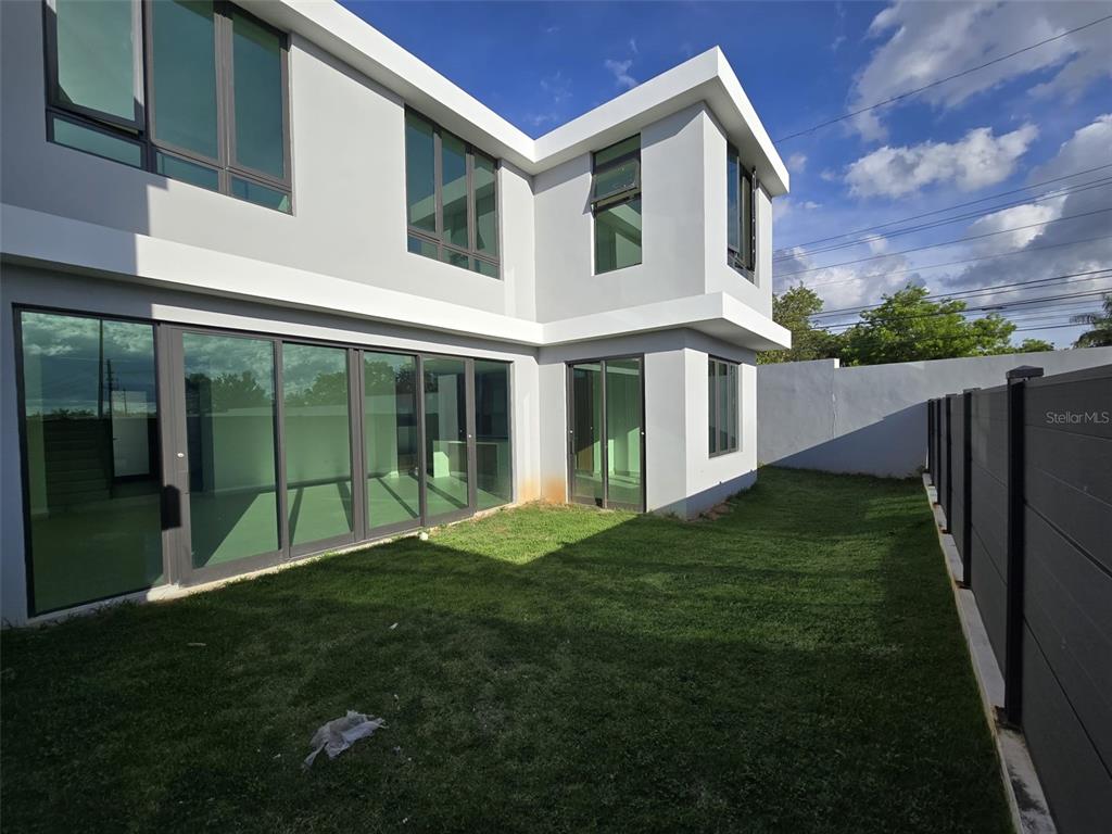 A modern two-story house with large glass sliding doors and a fenced backyard — PR 177 AVE LOMAS VERDES THE VILLAS AT RIO / BO JUAN SANCHEZ UNIT 79, BAYAMON, PR