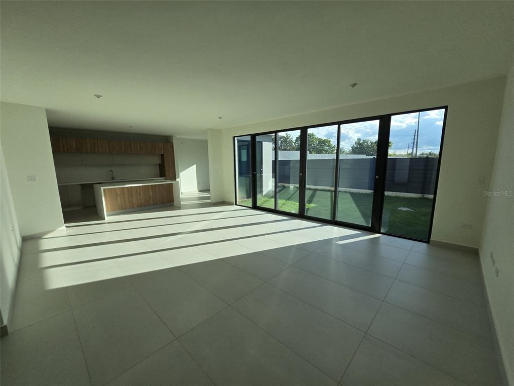 An open-concept living area features large glass sliding doors and a modern kitchen with wood cabinetry — PR 177 AVE LOMAS VERDES THE VILLAS AT RIO / BO JUAN SANCHEZ UNIT 79, BAYAMON, PR