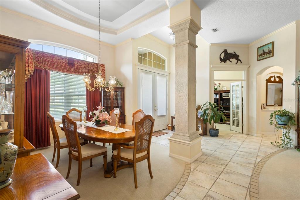 A dining room with a central stone pillar, tile and carpet flooring, and arched windows — 1621 TIMBER HILLS DRIVE, DELAND, FL