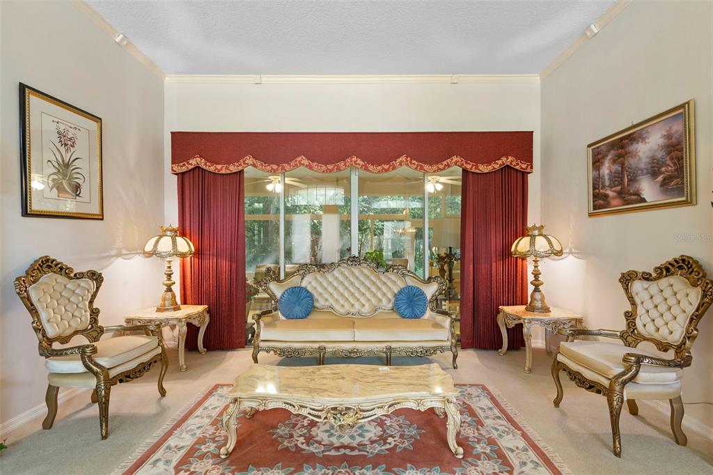 A formal living room features a tufted sofa, a grandfather clock, and tile flooring — 1621 TIMBER HILLS DRIVE, DELAND, FL