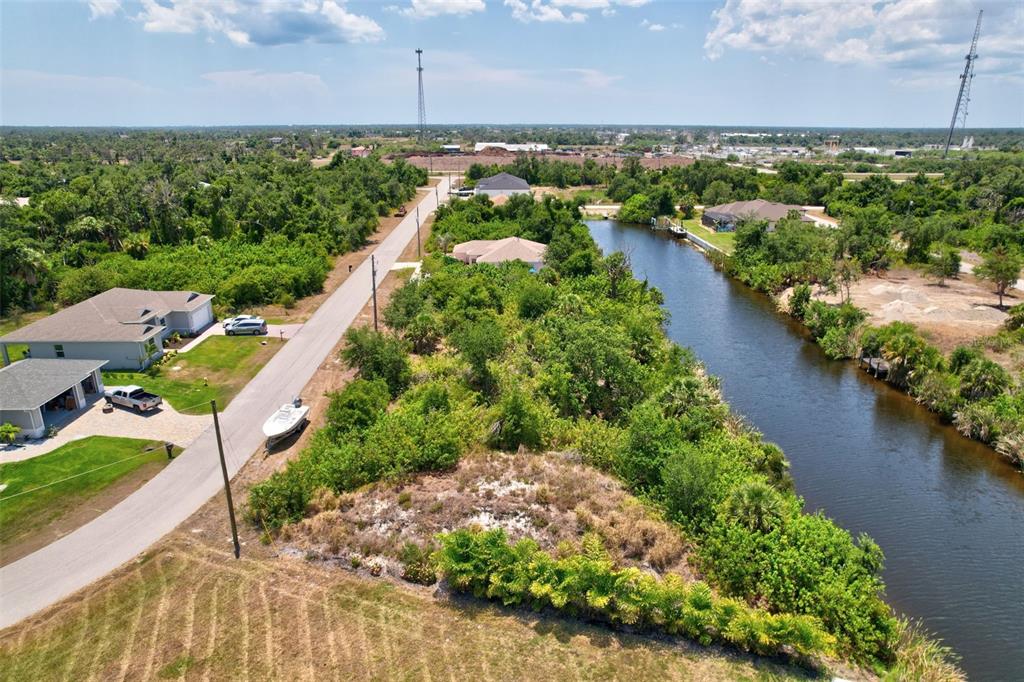 An aerial view shows a vacant lot situated between a paved road and a canal — 10080 COCOA BEACH STREET, PORT CHARLOTTE, FL