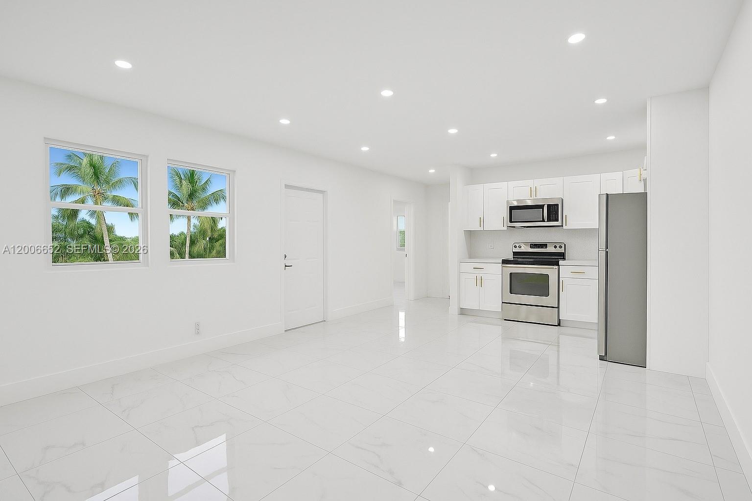 A bright, minimalist kitchen and living area features white cabinetry, stainless steel appliances, and tile flooring — 105 NW 14th Way # 0, Dania Beach FL 33004, DANIA BEACH, FL