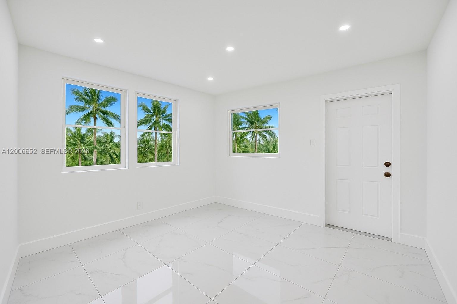 An empty room features white walls, large tile flooring, recessed lighting, and three windows — 105 NW 14th Way # 0, Dania Beach FL 33004, DANIA BEACH, FL