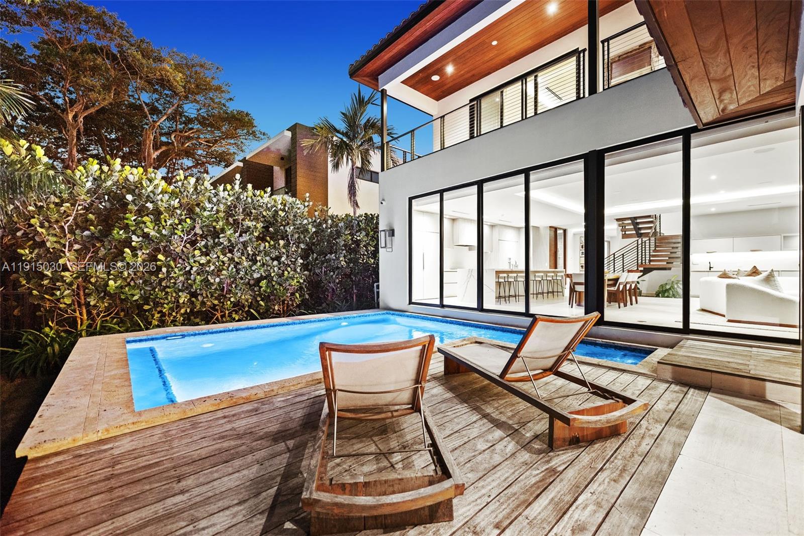 A swimming pool sits on a wooden deck outside a modern house with glass walls — 5831 Alton Rd, Miami Beach FL 33140, MIAMI BEACH, FL