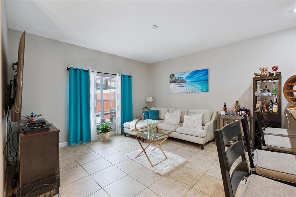 A living room features tile flooring, a sectional sofa, a glass coffee table, and blue curtains — 8957 CAT PALM ROAD, KISSIMMEE, FL