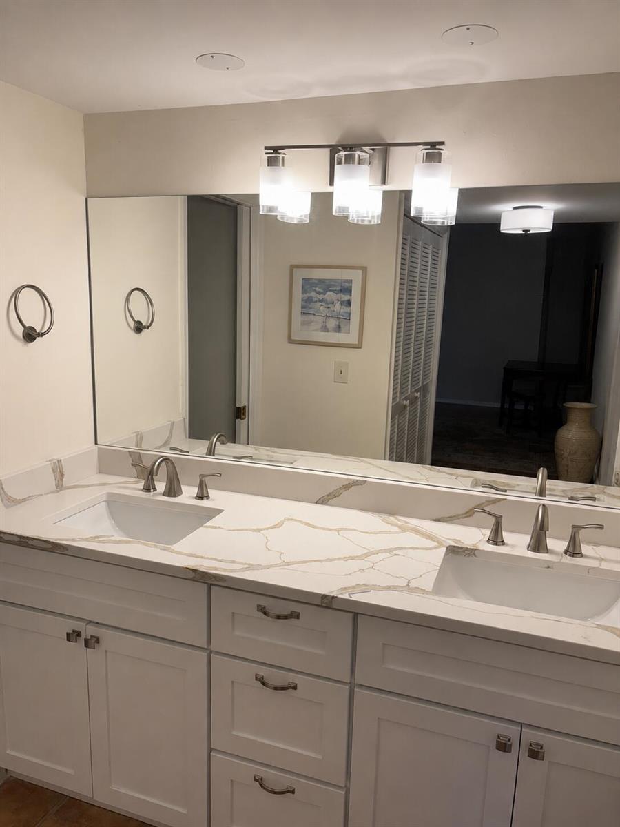 A bathroom vanity with a double sink, white cabinets, and a marble-patterned countertop — 11863 Wimbledon Circle # 441, Wellington FL 33414, WELLINGTON, FL