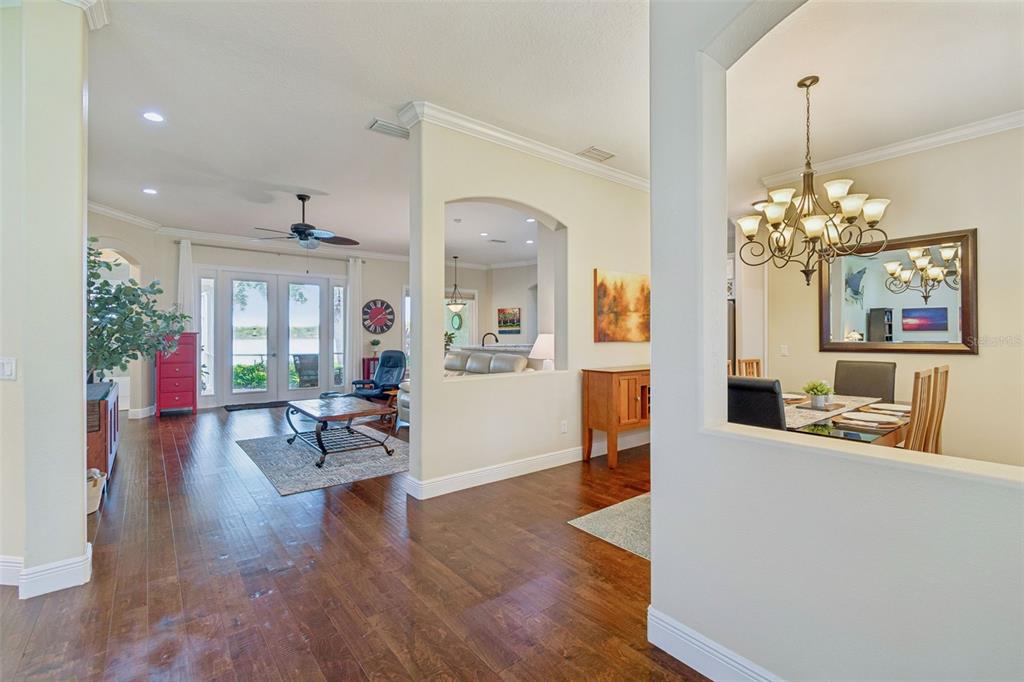 A view from a hallway into a living room and dining area with hardwood floors — 10035 REMINGTON DRIVE, RIVERVIEW, FL