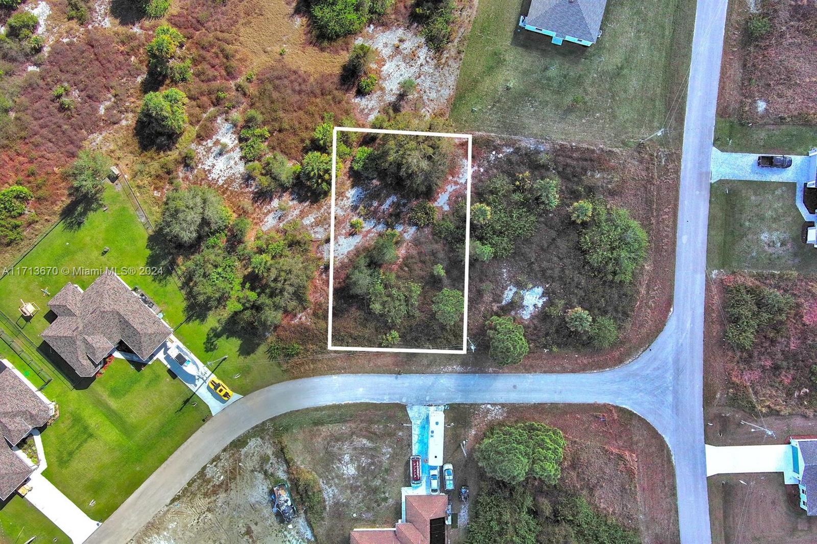 This aerial view shows a vacant, rectangular lot outlined in white within a residential neighborhood — 311 Raber Ave, Lehigh Acres FL 33974, LEHIGH ACRES, FL