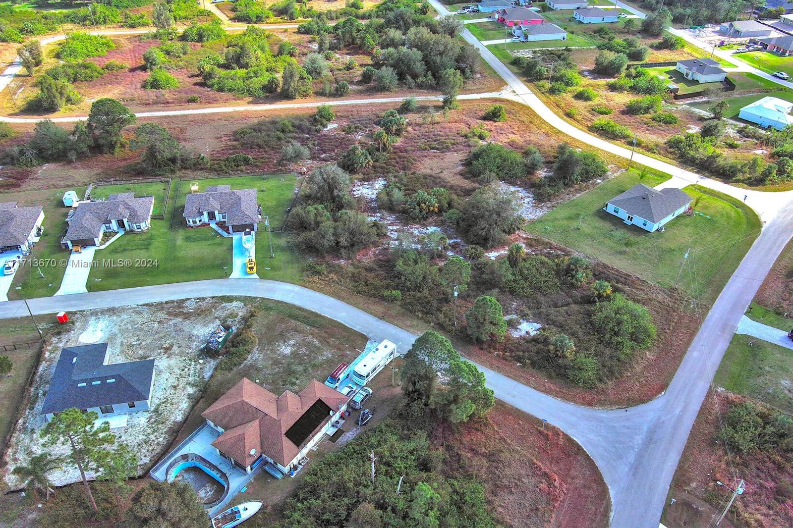 An aerial view shows several houses, a swimming pool, and undeveloped land in a rural area — 311 Raber Ave, Lehigh Acres FL 33974, LEHIGH ACRES, FL