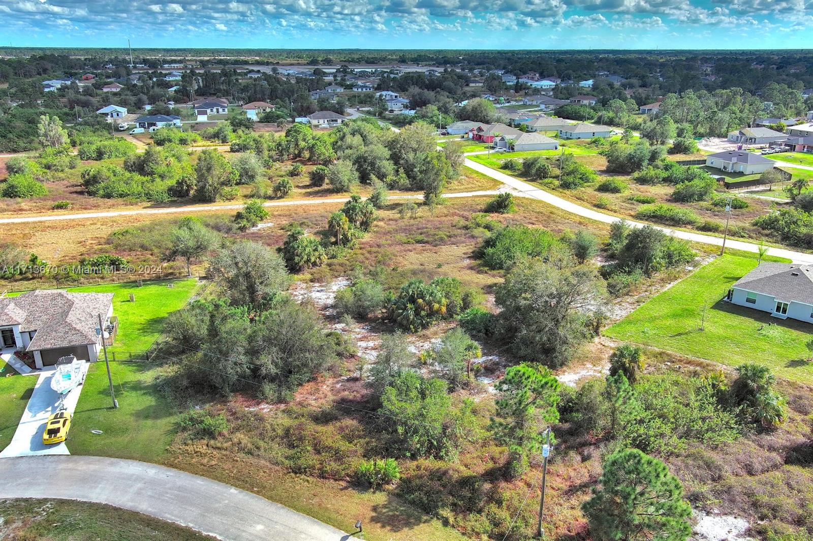 An aerial view shows a vacant, wooded residential lot situated between two existing suburban houses — 311 Raber Ave, Lehigh Acres FL 33974, LEHIGH ACRES, FL