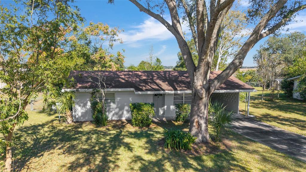 A single-story house with a gray exterior, a brown roof, and a large front tree — 21529 SW HONEYSUCKLE STREET, DUNNELLON, FL