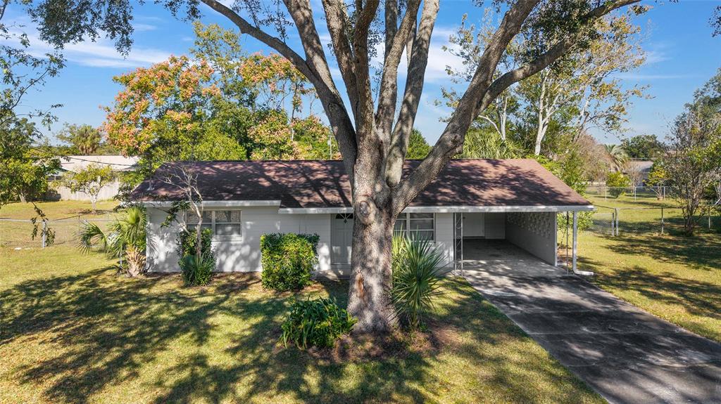 A single-story house with a carport and a large tree in the front yard — 21529 SW HONEYSUCKLE STREET, DUNNELLON, FL