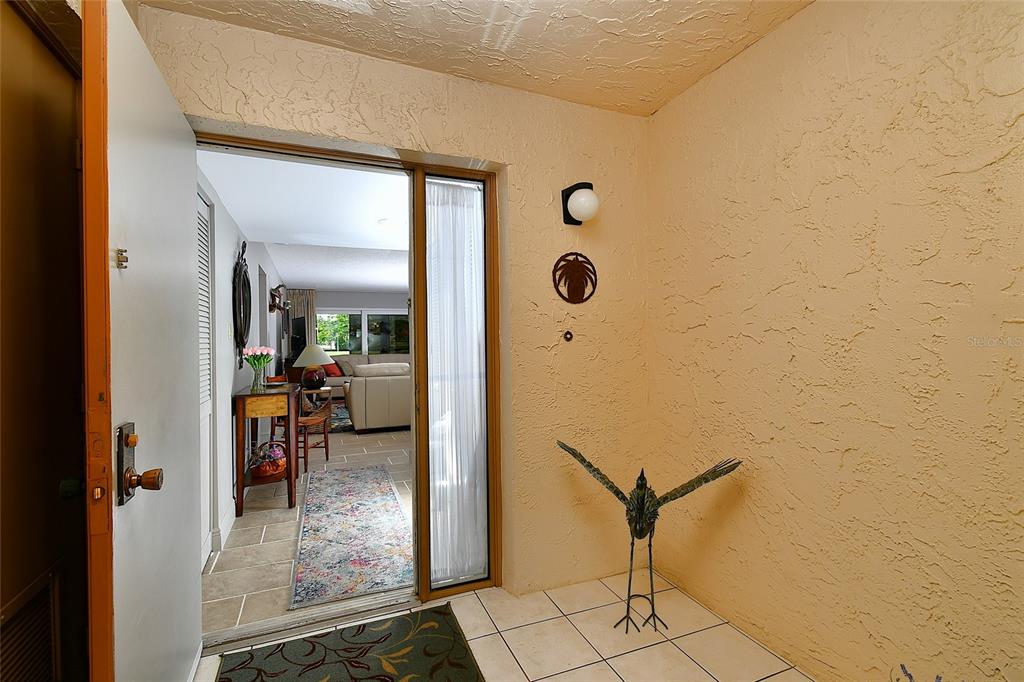 An entryway with a white door, tiled floor, and a metal bird sculpture — 1610 N ISLAMORADA BOULEVARD UNIT 62A, PUNTA GORDA, FL