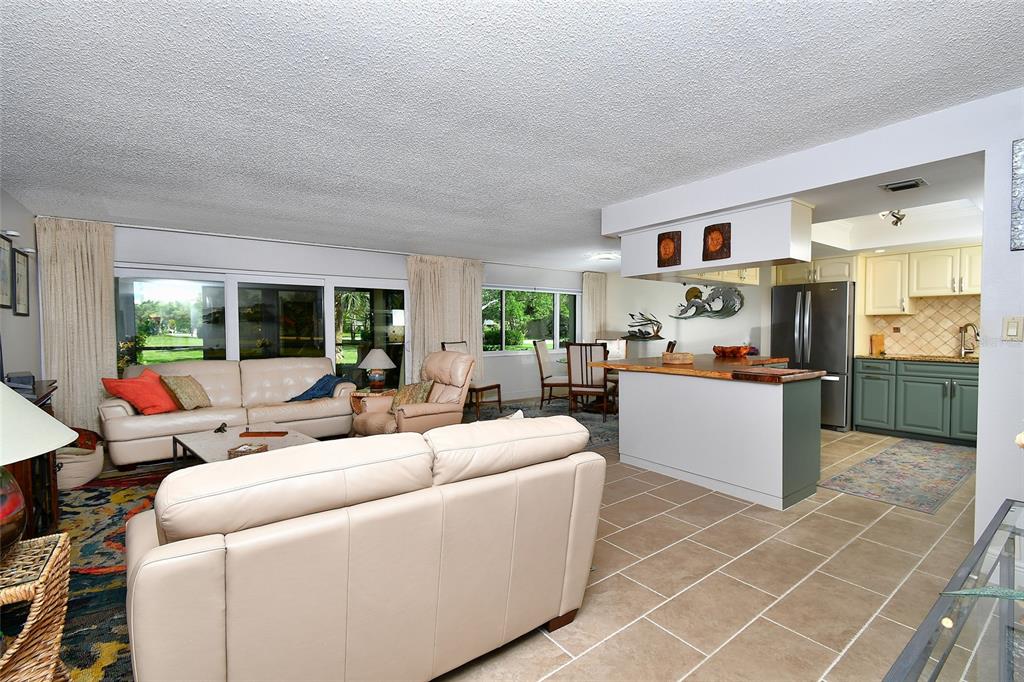 A living room with light-colored sofas and a kitchen with an island and green cabinets — 1610 N ISLAMORADA BOULEVARD UNIT 62A, PUNTA GORDA, FL