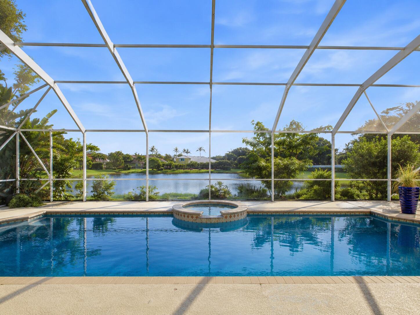 A screened-in swimming pool and spa overlooking a lake with surrounding trees and houses — 7209 Serrano Terrace, Delray Beach FL 33446, DELRAY BEACH, FL