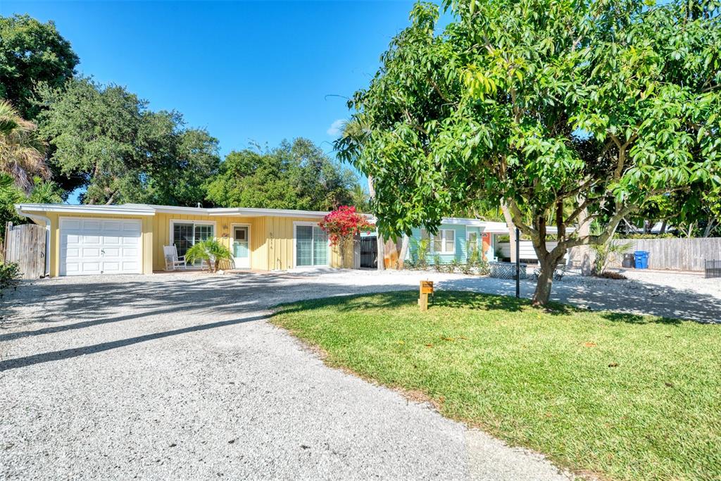 A yellow single-story house with a gravel driveway and a large tree in the yard — 5216 CALLE DE COSTA RICA, SARASOTA, FL