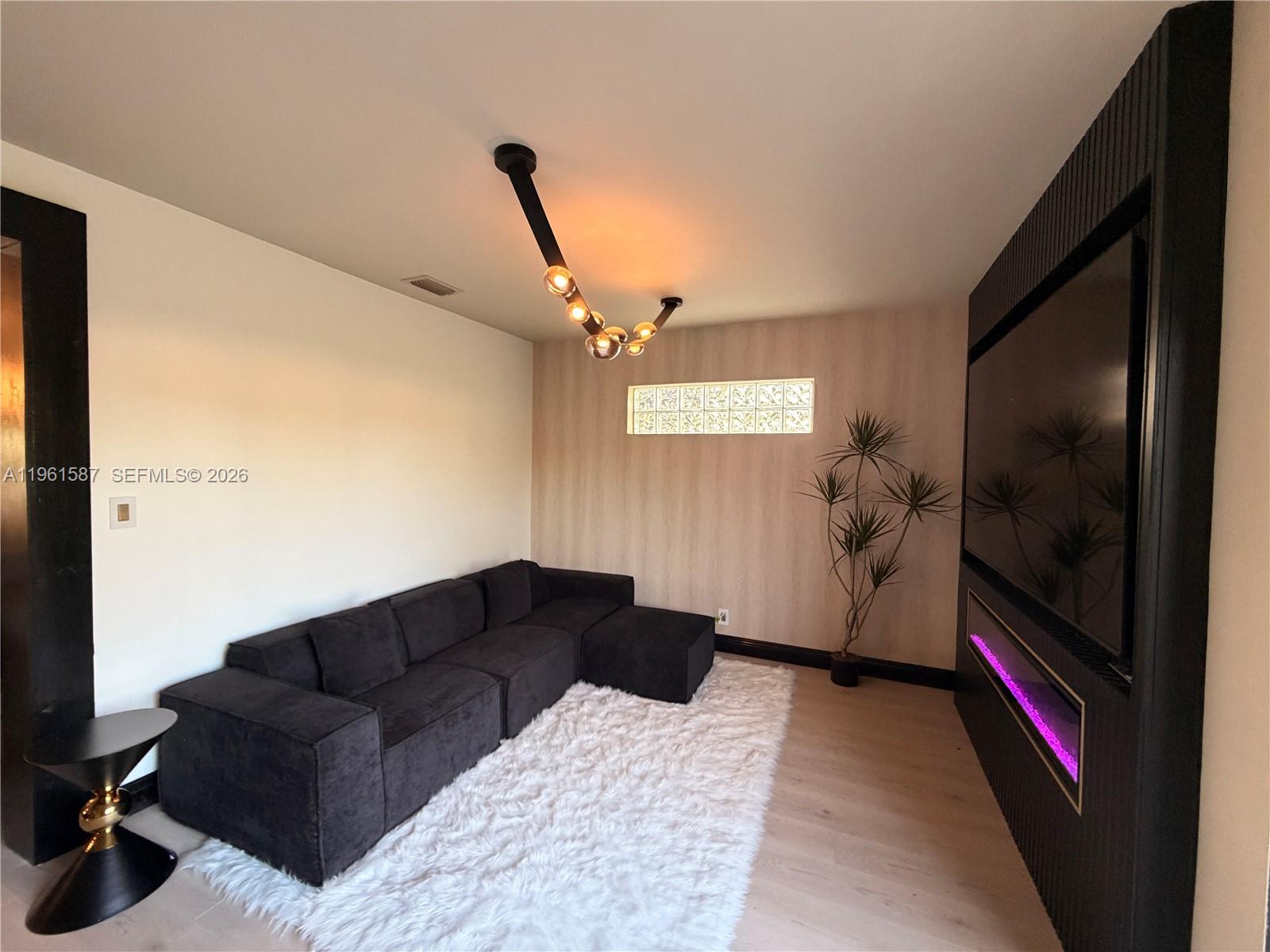 A modern living room features a black sectional sofa, a fireplace, and a glass block window — 920 SW 50th Ave, Plantation FL 33317, PLANTATION, FL