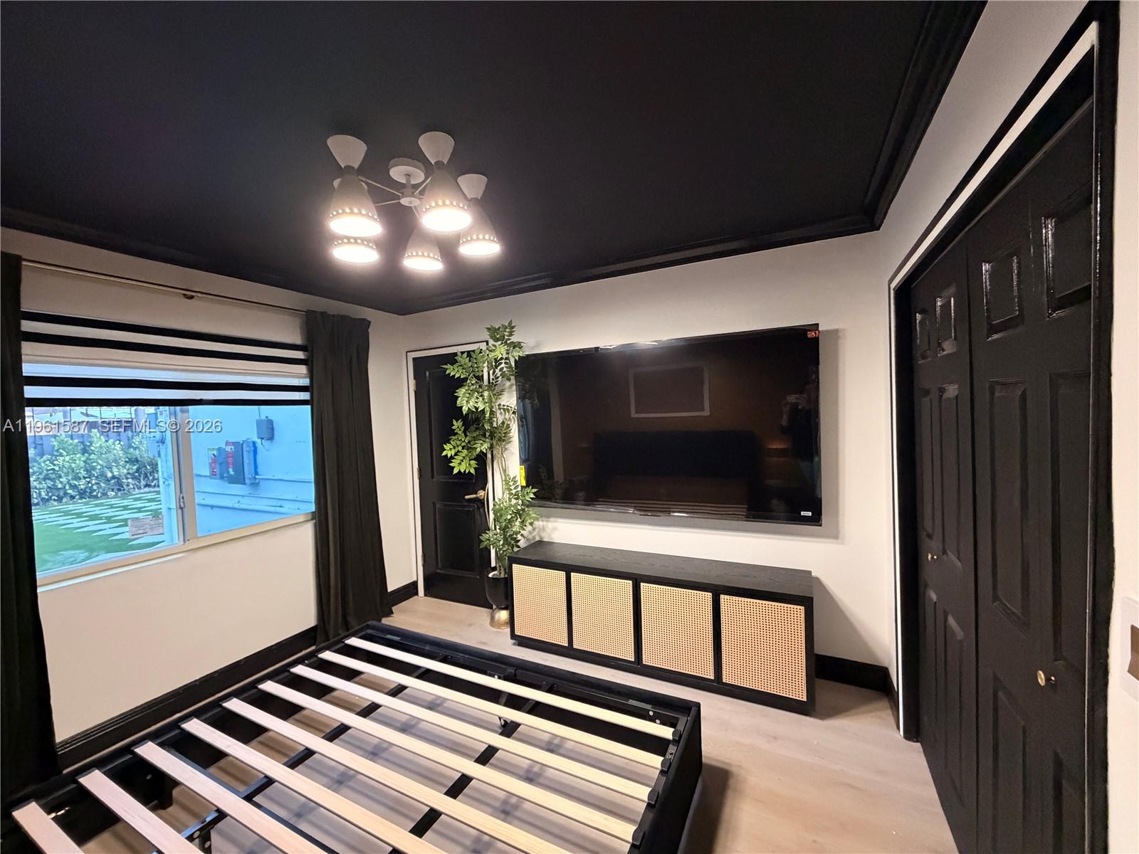 A bedroom features a black ceiling, black doors, a wall-mounted television, and a bed frame — 920 SW 50th Ave, Plantation FL 33317, PLANTATION, FL