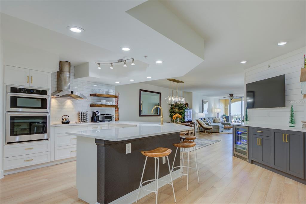 A modern kitchen features a white island, dark lower cabinets, and stainless steel appliances — 5353 GULF BOULEVARD UNIT A502, ST PETE BEACH, FL