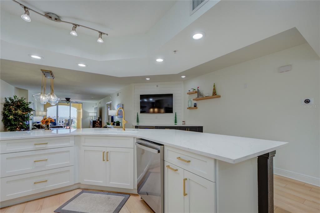 A modern kitchen features white cabinets, a quartz island countertop, and stainless steel appliances — 5353 GULF BOULEVARD UNIT A502, ST PETE BEACH, FL