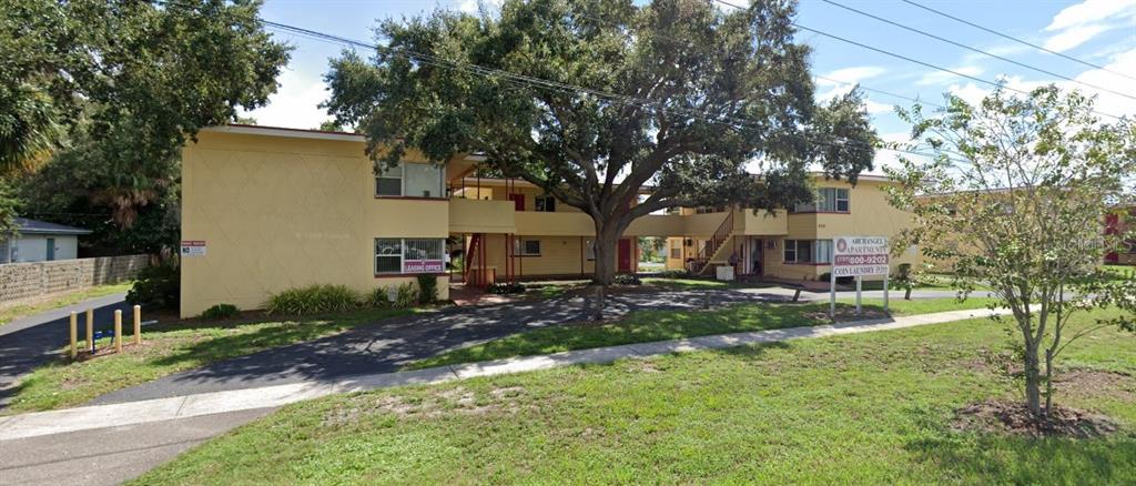 A two-story yellow apartment building with a large tree in the front courtyard — 1050 62ND AVE SOUTH UNIT E-4, ST PETERSBURG, FL