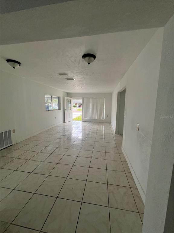 A bright, empty room features white walls, tiled flooring, and a glass-paned exterior door — 14405 DARING AVENUE, ORLANDO, FL