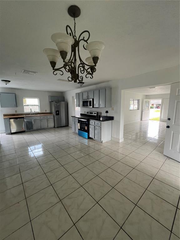An open-concept kitchen features gray cabinets, stainless steel appliances, and light-colored tile flooring — 14405 DARING AVENUE, ORLANDO, FL