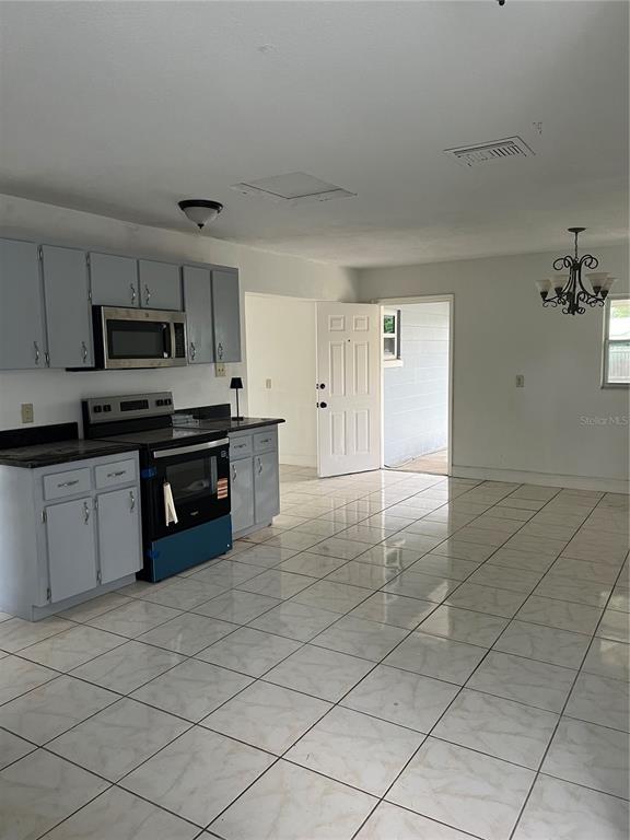 A kitchen with light blue cabinets, stainless steel appliances, and white tiled flooring — 14405 DARING AVENUE, ORLANDO, FL
