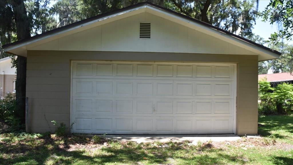 A detached garage with a white sectional door and a beige exterior — 105 KENT COURT, PORT ORANGE, FL