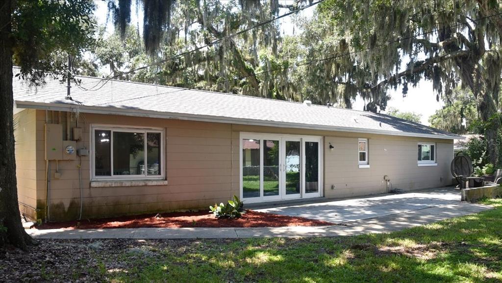 The exterior of a single-story house features tan siding, a concrete patio, and sliding doors — 105 KENT COURT, PORT ORANGE, FL
