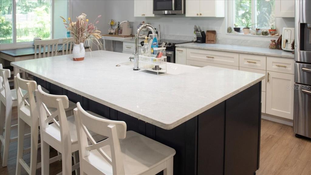 A kitchen island with a white countertop and dark base sits in front of white cabinets — 105 KENT COURT, PORT ORANGE, FL