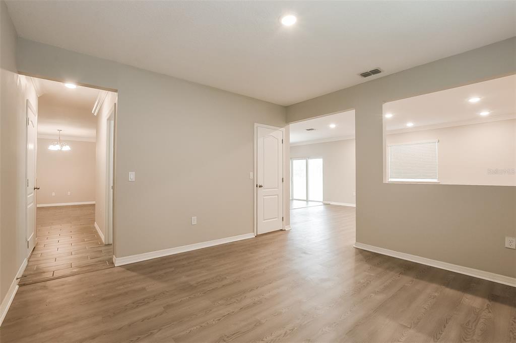 An interior view shows a room with light gray walls, wood-look flooring, and multiple doorways — 1926 BELL CREEK LOOP, FRUITLAND PARK, FL
