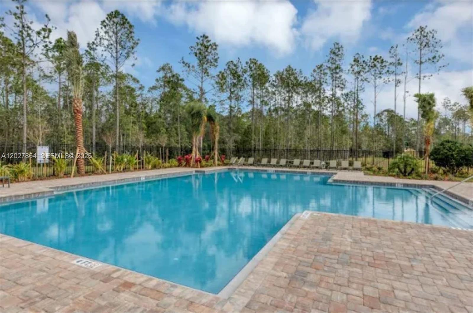 A modern kitchen with white cabinets and a gray island opens to a living area — 1122 Cabot Cliffs Dr, Daytona FL 32124, DAYTONA, FL