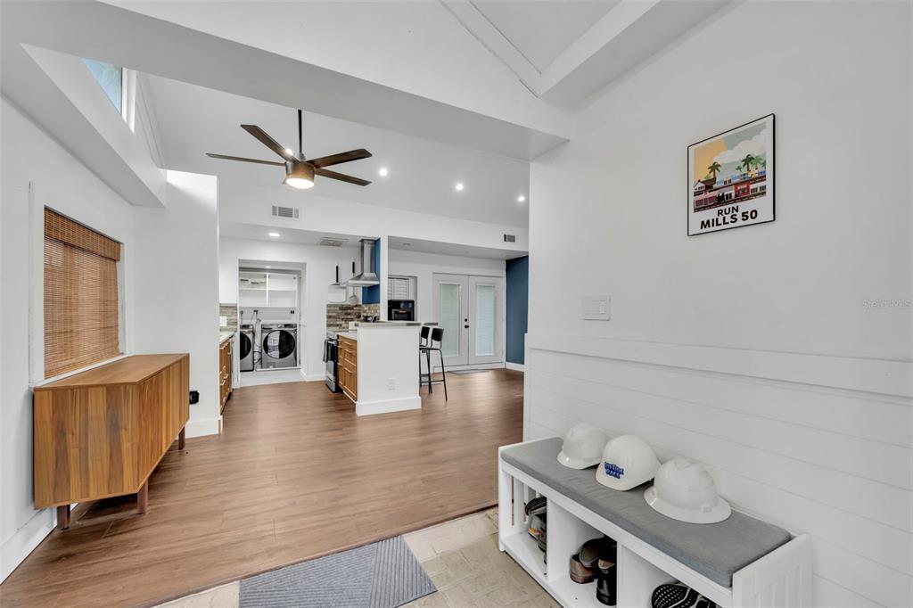 A white-walled entryway leads into an open-concept kitchen and living area with wood flooring — 817 ALTALOMA AVENUE, ORLANDO, FL
