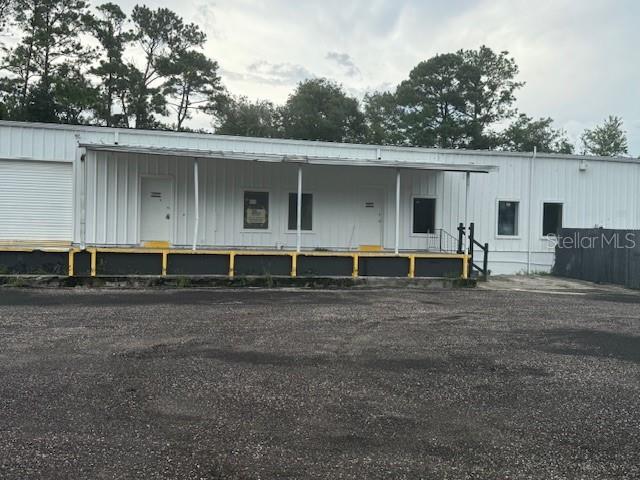 A white industrial warehouse building features a loading dock and a gravel parking lot — 479 ZOO PARKWAY, JACKSONVILLE, FL