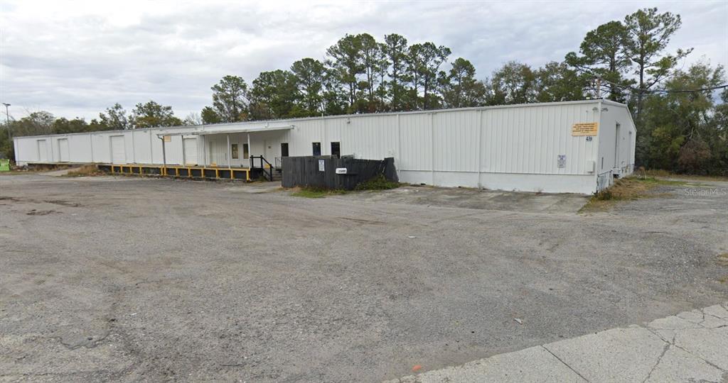 A long, white industrial warehouse building features a loading dock and a gravel parking lot — 479 ZOO PARKWAY, JACKSONVILLE, FL