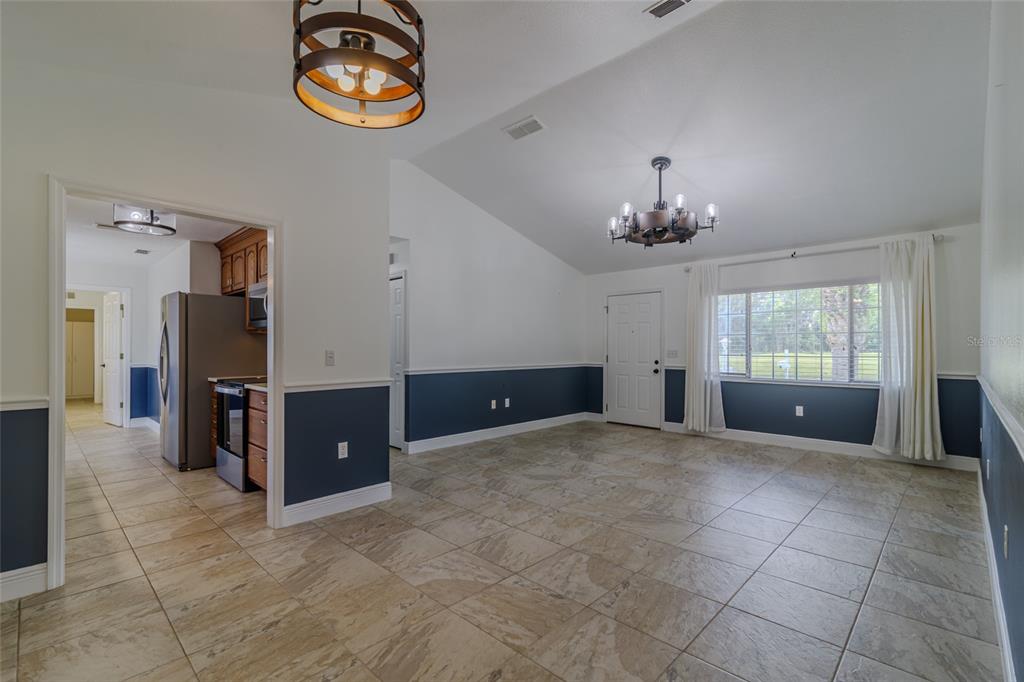 A dining area with tile flooring, blue wainscoting, and two hanging chandeliers — 5143 NW 18TH STREET, OCALA, FL