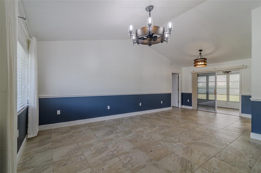 A dining room with tile floors, blue wainscoting, and two rustic chandeliers — 5143 NW 18TH STREET, OCALA, FL