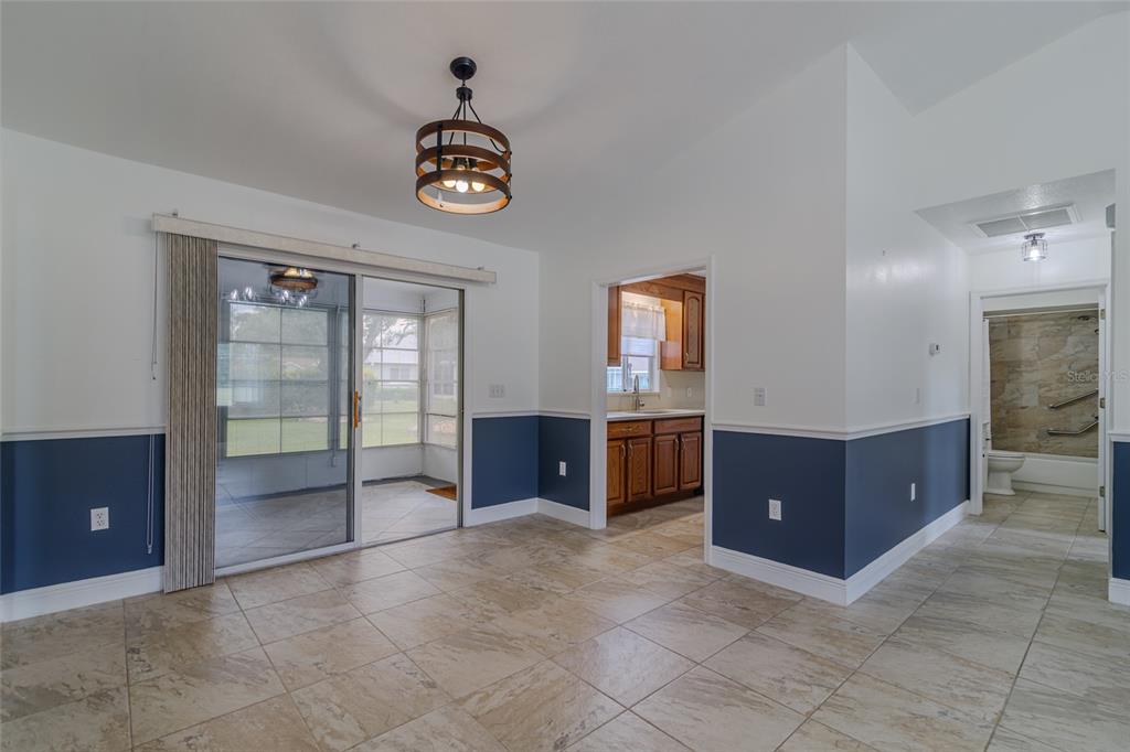 A dining area with tile floors, blue wainscoting, a sliding glass door, and a chandelier — 5143 NW 18TH STREET, OCALA, FL