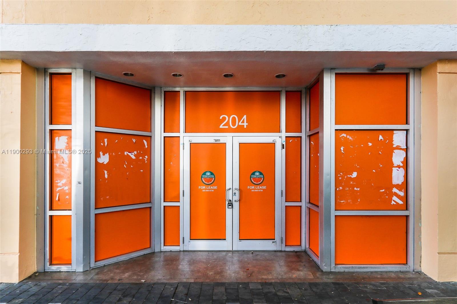 The exterior entrance of a commercial storefront features orange window panels and double glass doors — 204 Miracle Mile, Coral Gables FL 33134, CORAL GABLES, FL
