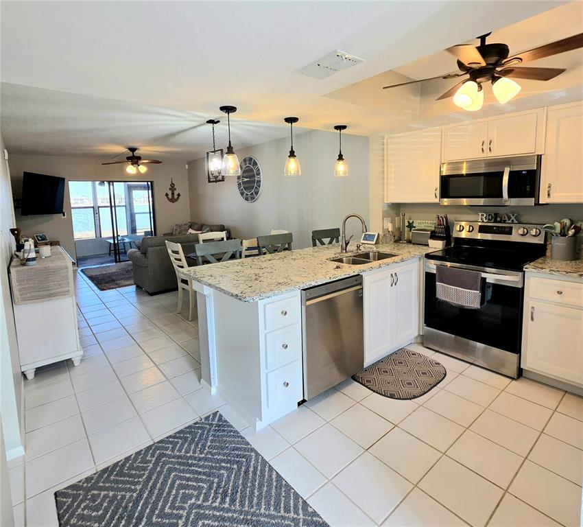 A kitchen with white cabinets and granite countertops opens into a living area with water views — 25225 RAMPART BOULEVARD UNIT 303, PUNTA GORDA, FL