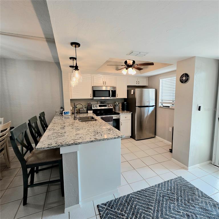 A kitchen features white cabinets, granite countertops, stainless steel appliances, and a breakfast bar — 25225 RAMPART BOULEVARD UNIT 303, PUNTA GORDA, FL