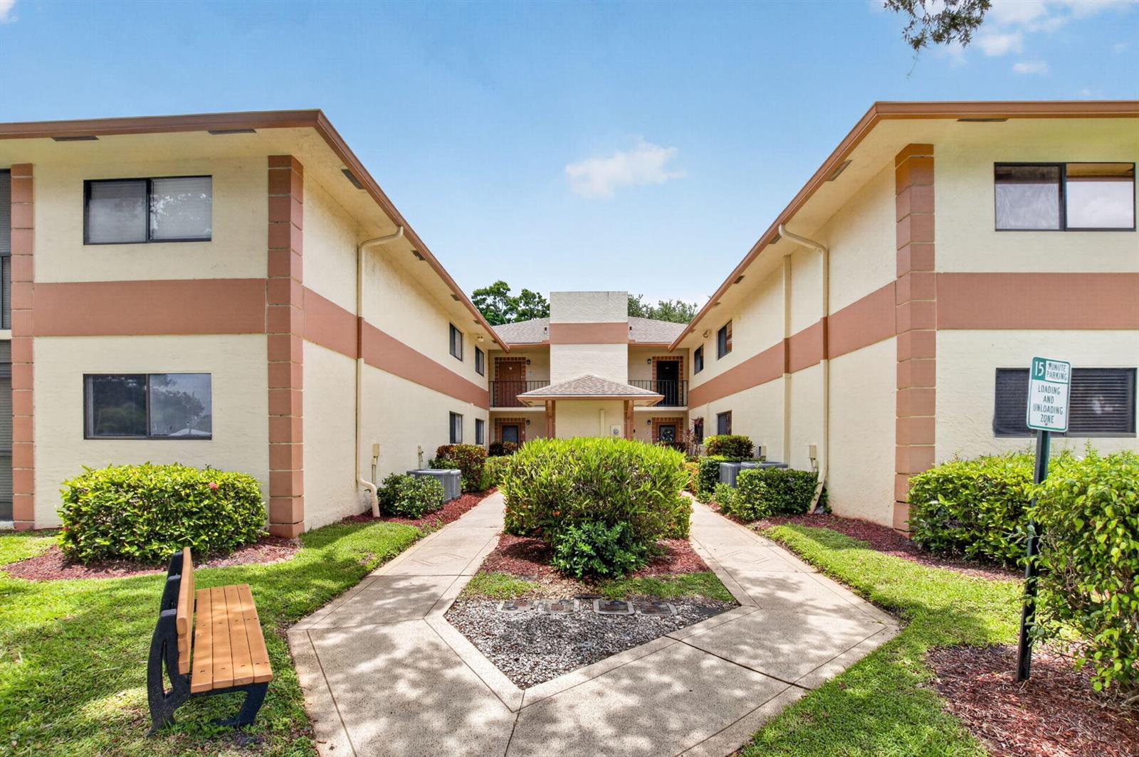 An exterior view of a two-story apartment building with a central walkway and landscaping — 15401 Pembridge Avenue # 15, Delray Beach FL 33484, DELRAY BEACH, FL