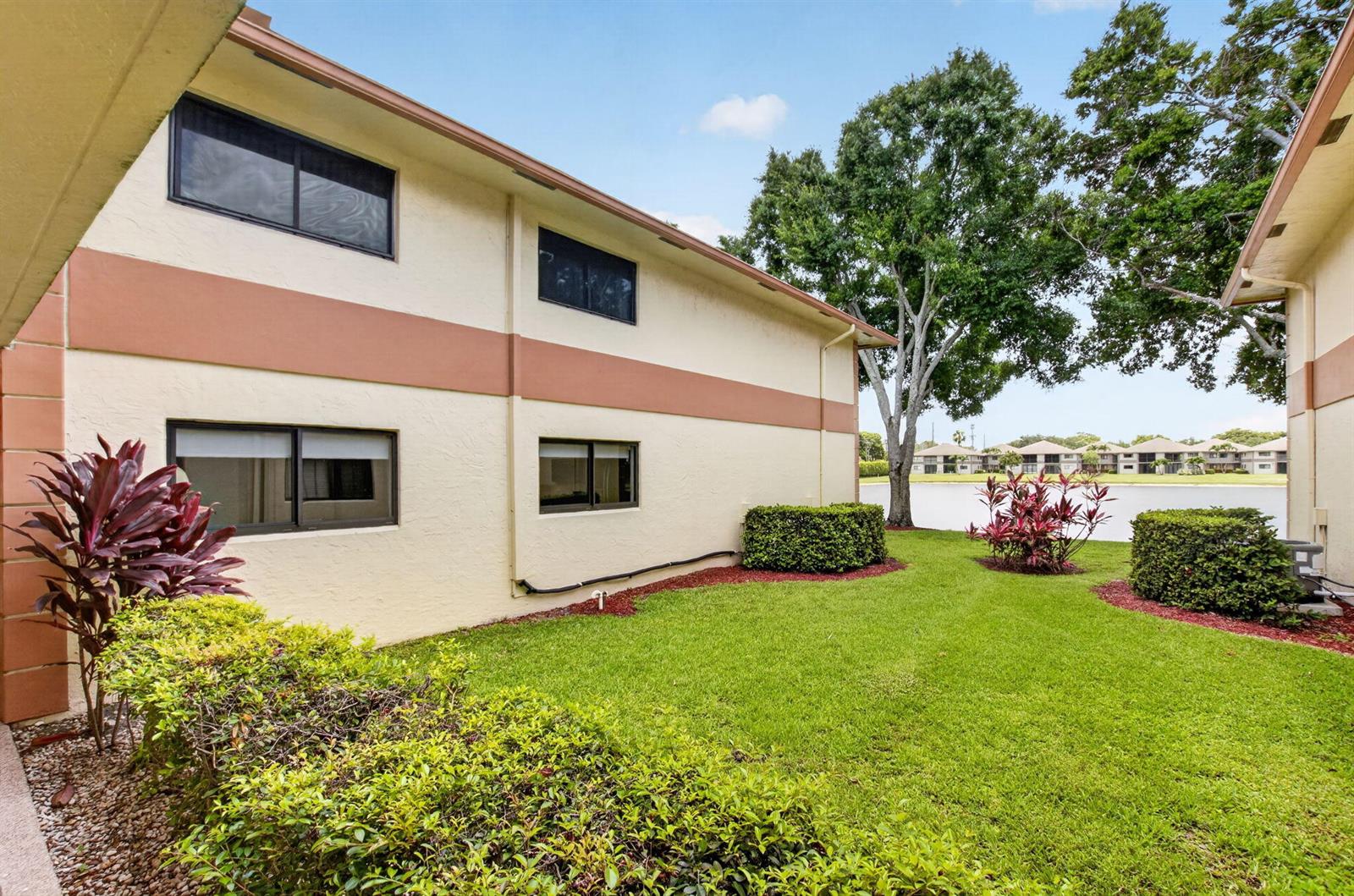 A view of a grassy courtyard between two apartment buildings with a lake in back — 15401 Pembridge Avenue # 15, Delray Beach FL 33484, DELRAY BEACH, FL