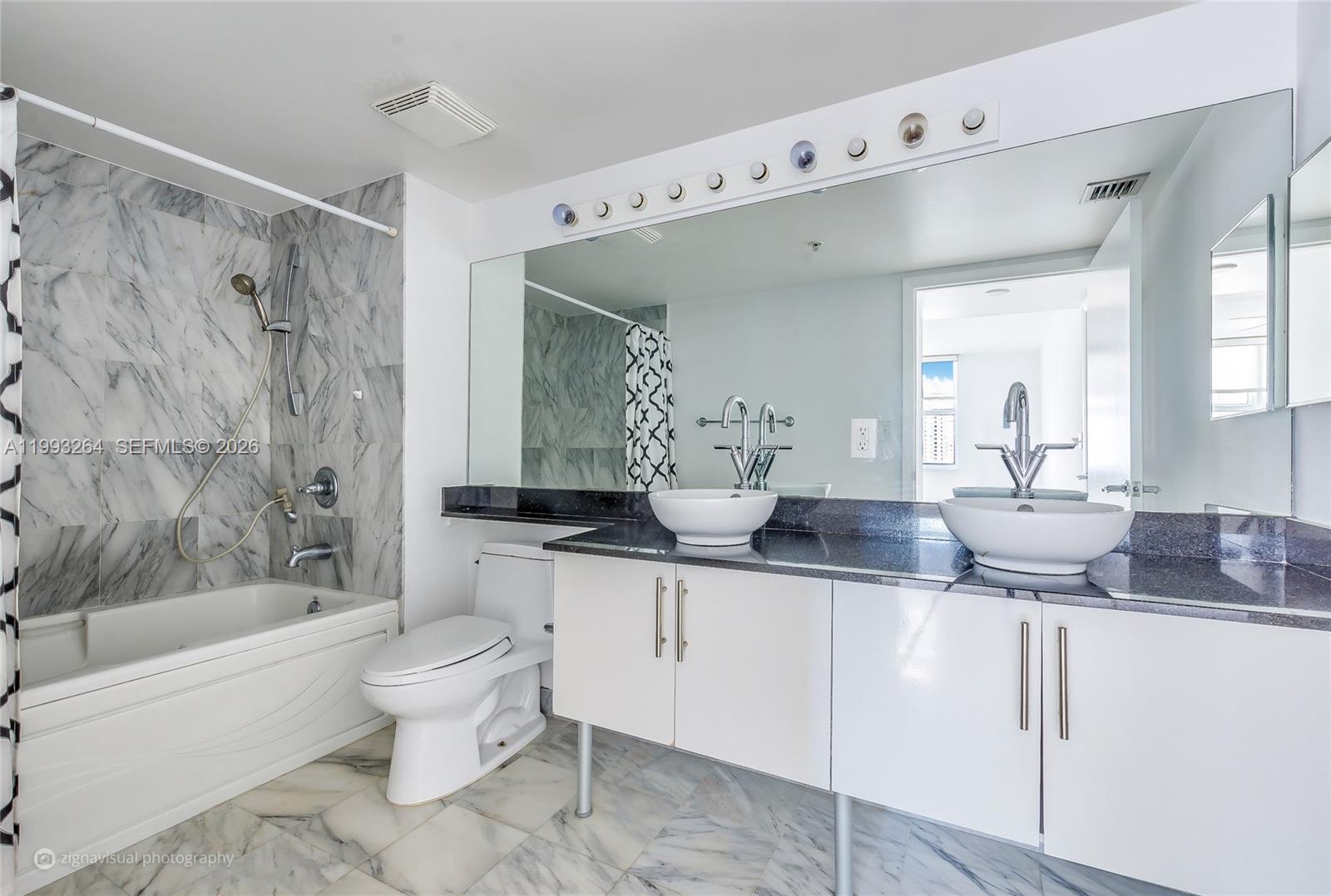 A bathroom features a double vanity with vessel sinks, a marble-tiled tub, and white cabinetry — 31 SE 5th St # 2708, Miami FL 33131, MIAMI, FL