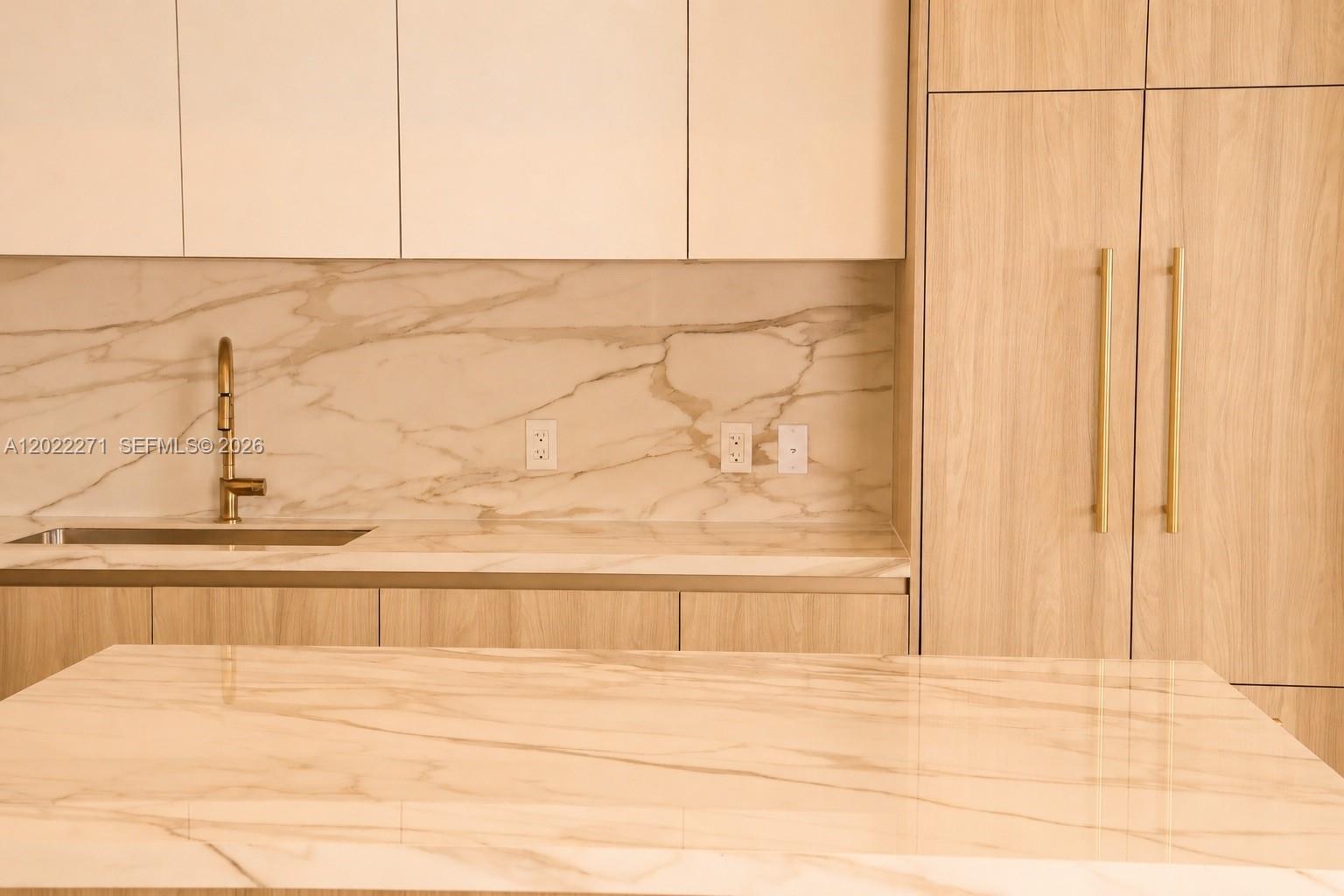 A modern kitchen features light wood cabinetry, white marble countertops, and a matching marble backsplash — 77 SE 5 St, Miami FL 33131, MIAMI, FL