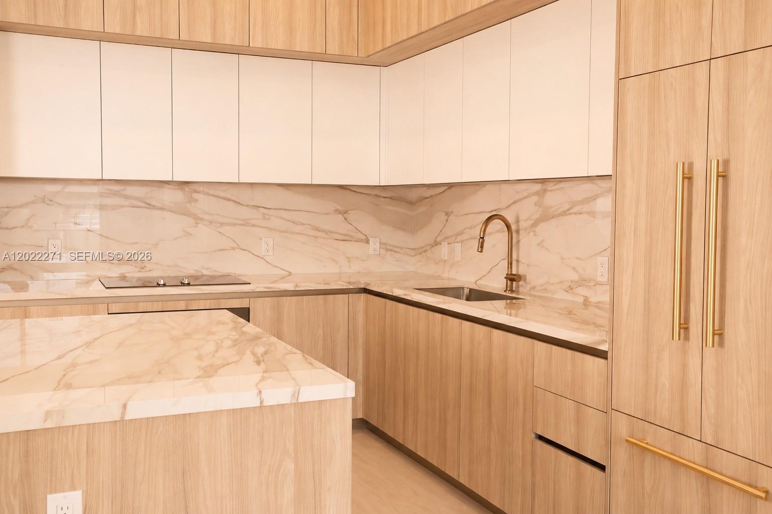 A modern kitchen features light wood cabinetry, white upper cabinets, and marble countertops — 77 SE 5 St, Miami FL 33131, MIAMI, FL
