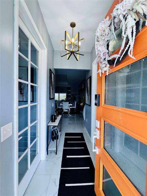 An entryway features a bright orange front door, a modern chandelier, and a black runner — 494 MARION OAKS DRIVE, OCALA, FL