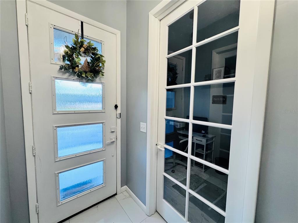 A white front door with glass panels sits next to a French door leading inside — 494 MARION OAKS DRIVE, OCALA, FL
