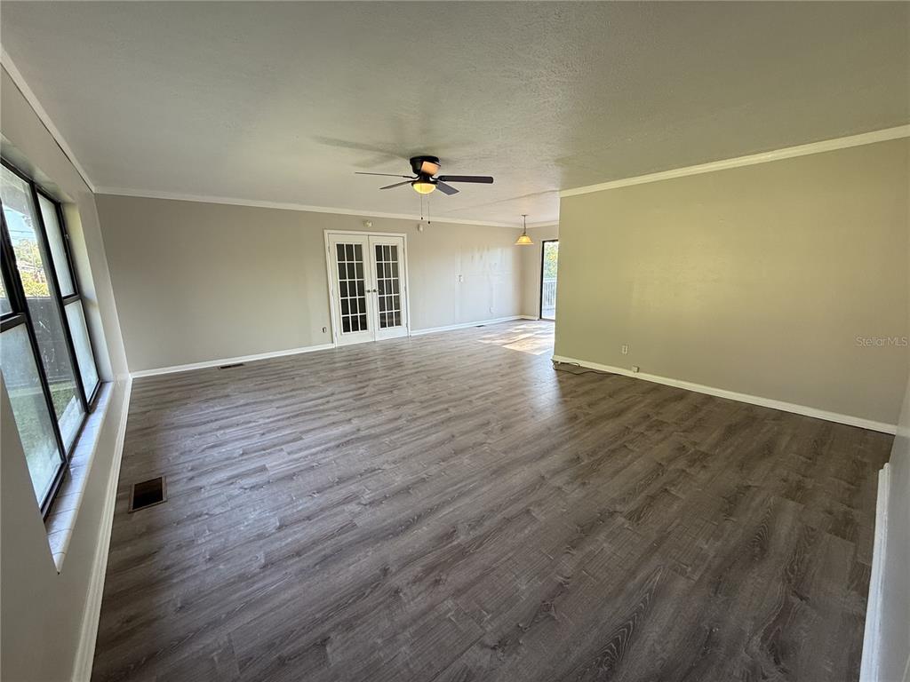 A spacious living room features light gray walls, wood-look flooring, and white French doors — 307 S ORANGE AVENUE, DELAND, FL